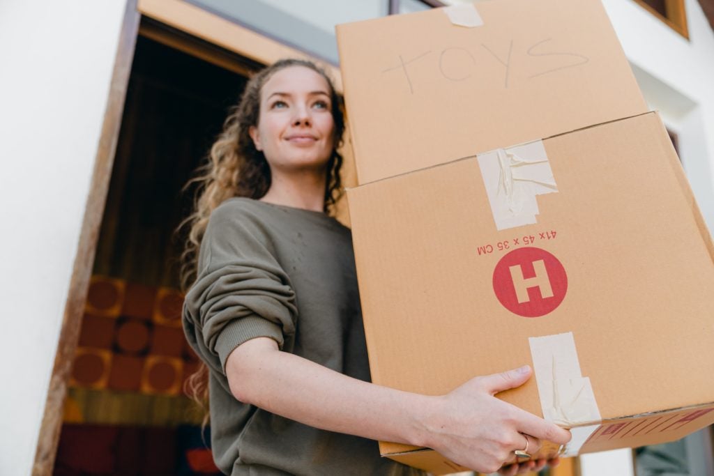 Person carrying cardboard boxes labeled toys