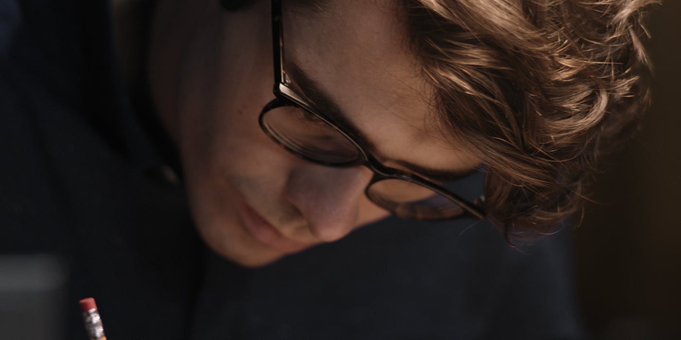 Person writing with pencil indoors