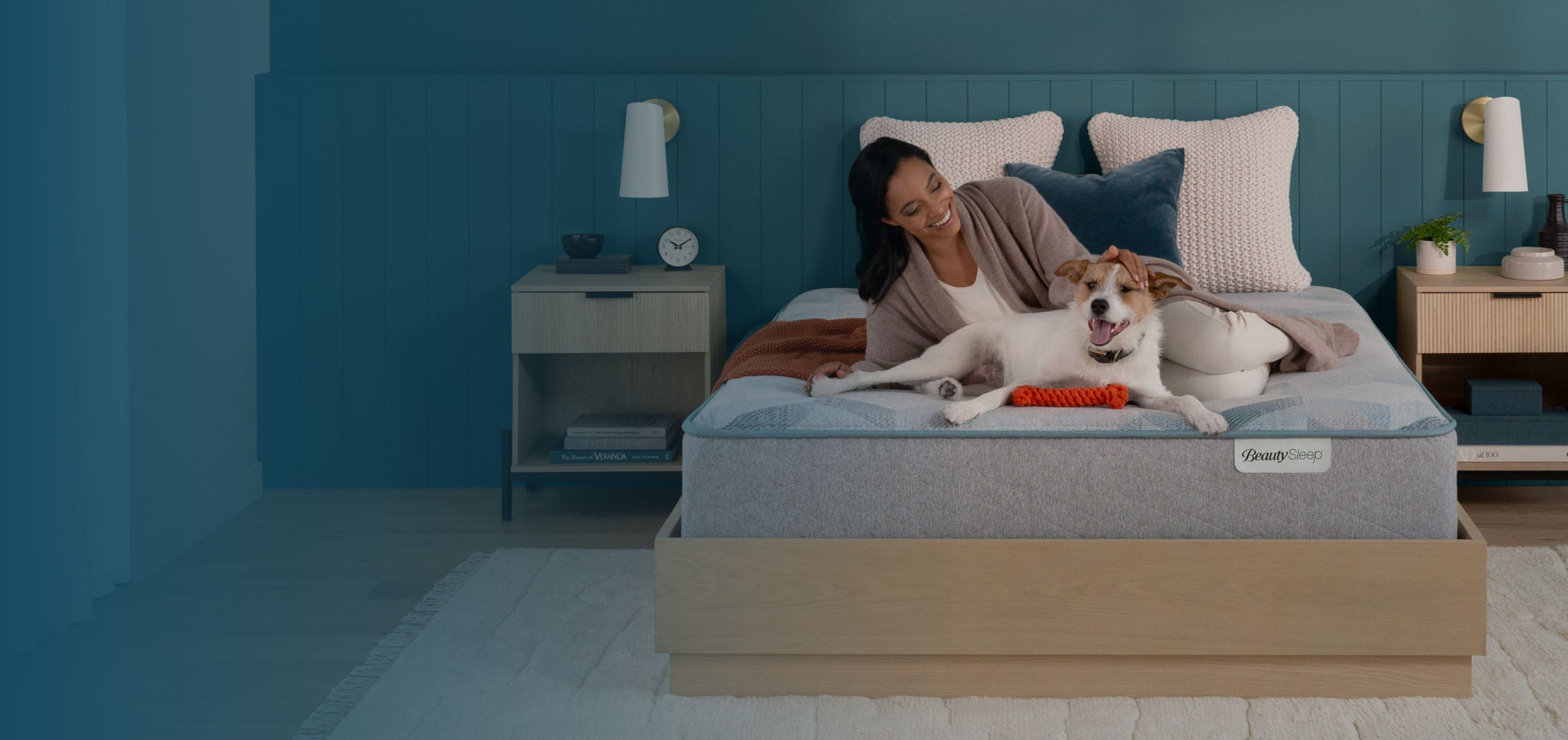 Man with his dog sitting on a Beautyrest mattress slightly elevated on an adjustable base