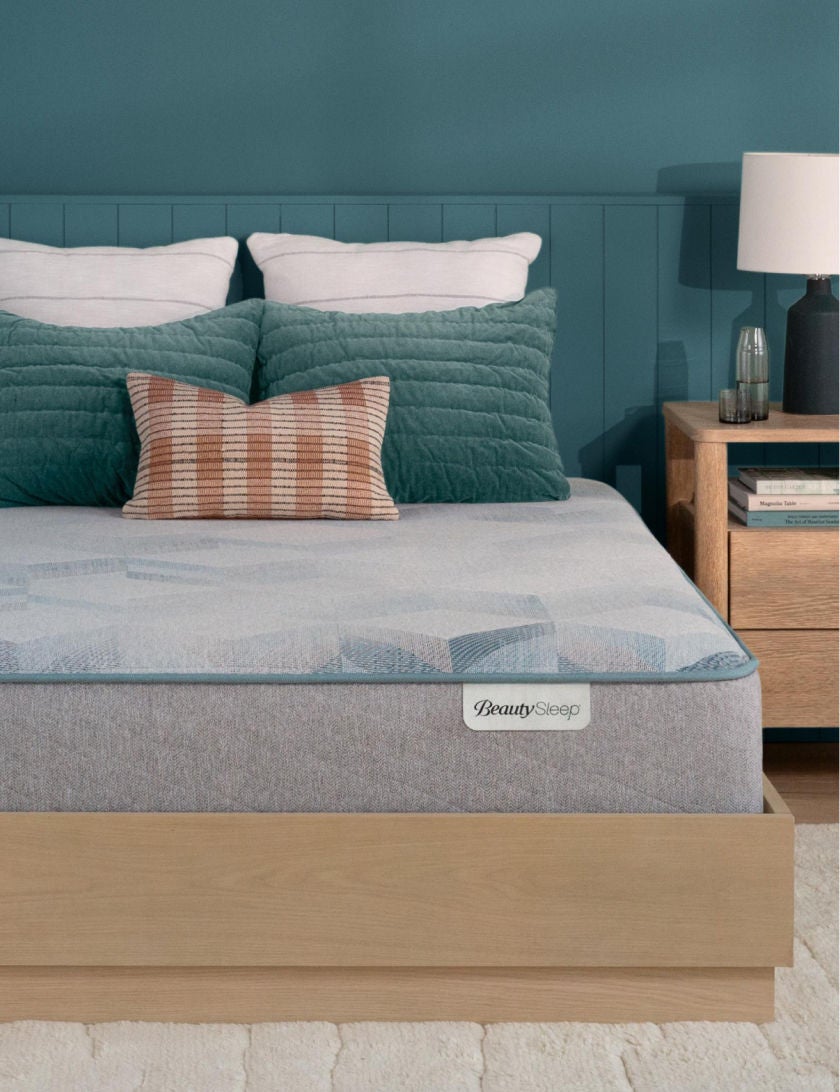 Beautysleep Dream Weaver Hybrid mattress in a brown bedframe with 5 pillows on top