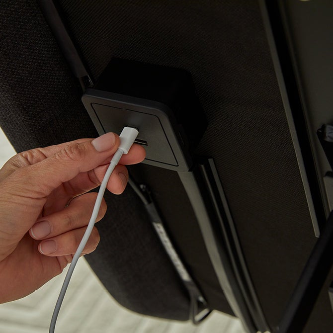 Hand plugging cable into furniture USB port