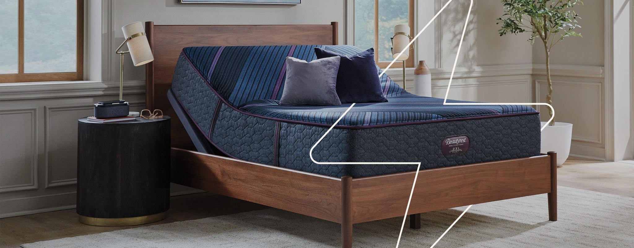 Beautyrest mattress sitting on an adjustable base slightly elevated at the top in a brown bed frame with 2 pillows on top of it.