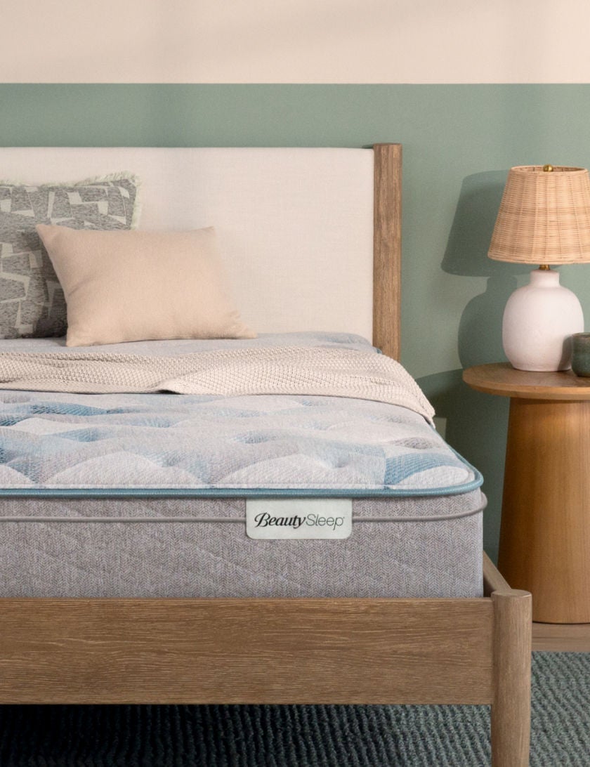 Beautysleep Dream Weaver Quilted Innerspring mattress in a brown bedframe with 2 pillows and 1 blanket on top