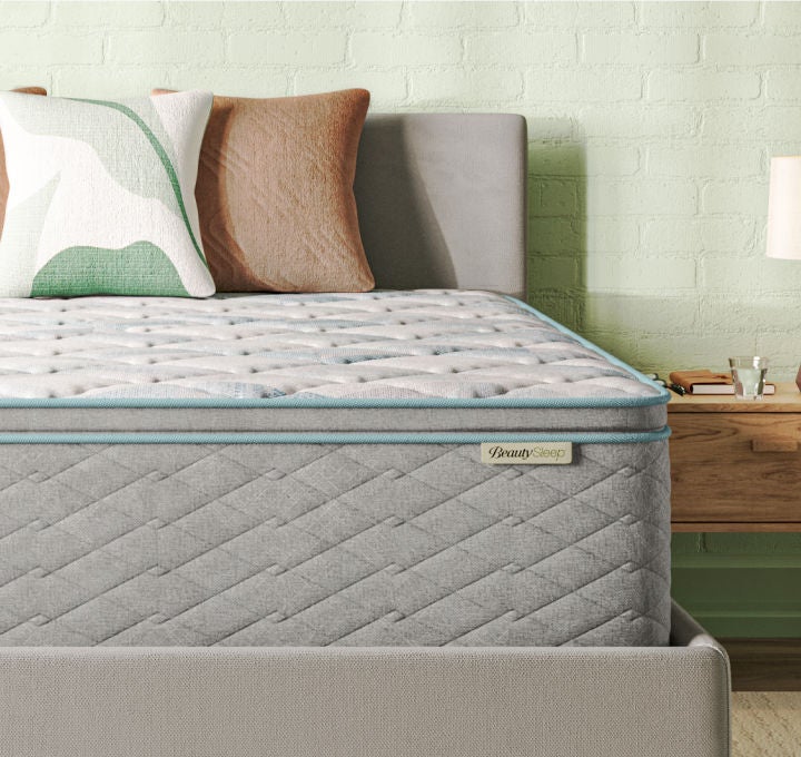 Corner of a Beautysleep Mattress in a Box in a grey bedframe with 2 pillows on top.