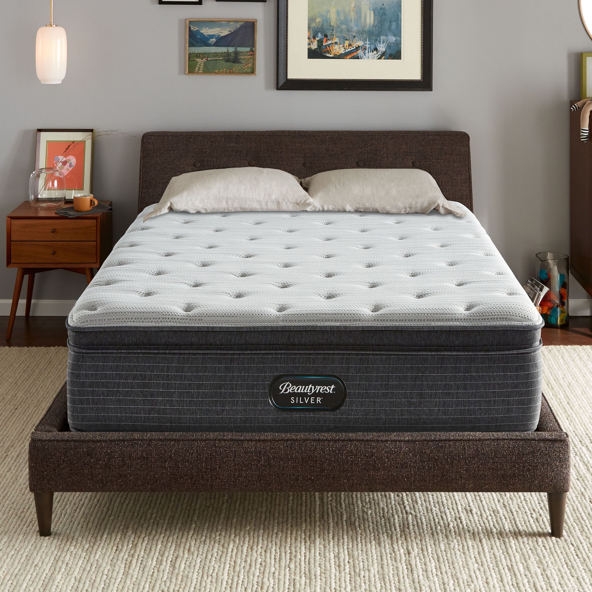 The Beautyrest Silver BRS900 Plush Pillow Top mattress in a bedroom on a brown bed