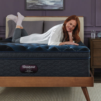 Woman laying on a Beautyrest World Class mattress on her stomach rubbing on her right hand on the top of the mattress.