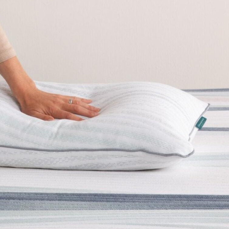 A hand pressing on a soft, white down pillow resting on a Beautyrest mattress, emphasizing plush comfort, best suited for side and back sleepers.