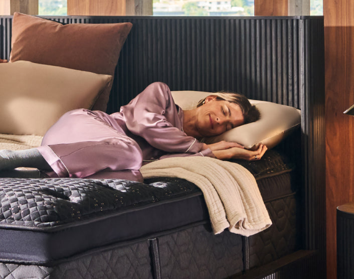 Woman laying asleep on a BeautyRest Black mattress, on her left side