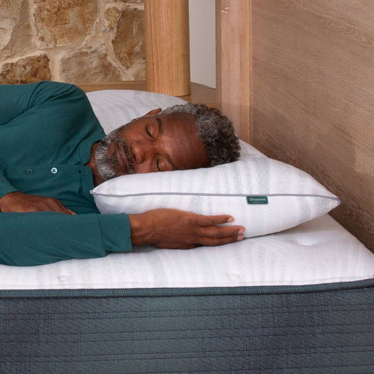 A man sleeping in bed on the Beautyrest Harmony Lux pillow