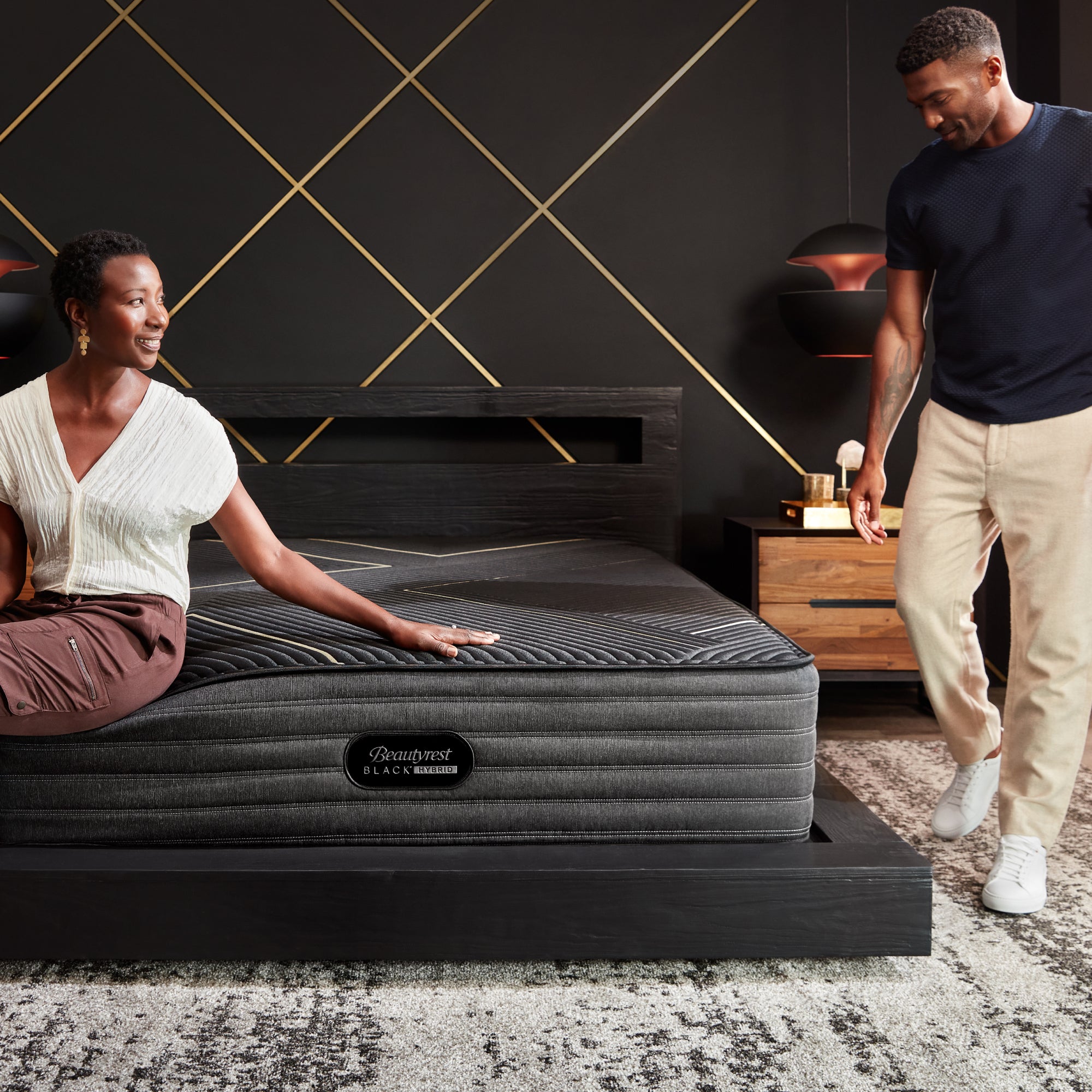 A Couple standing around the Beautyrest Black hybrid mattress in a bedroom||series: exceptional kx-class