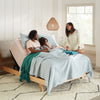 Two parents and a child in a bedroom on the  Beautyrest Motion Air adjustable base with a mattress