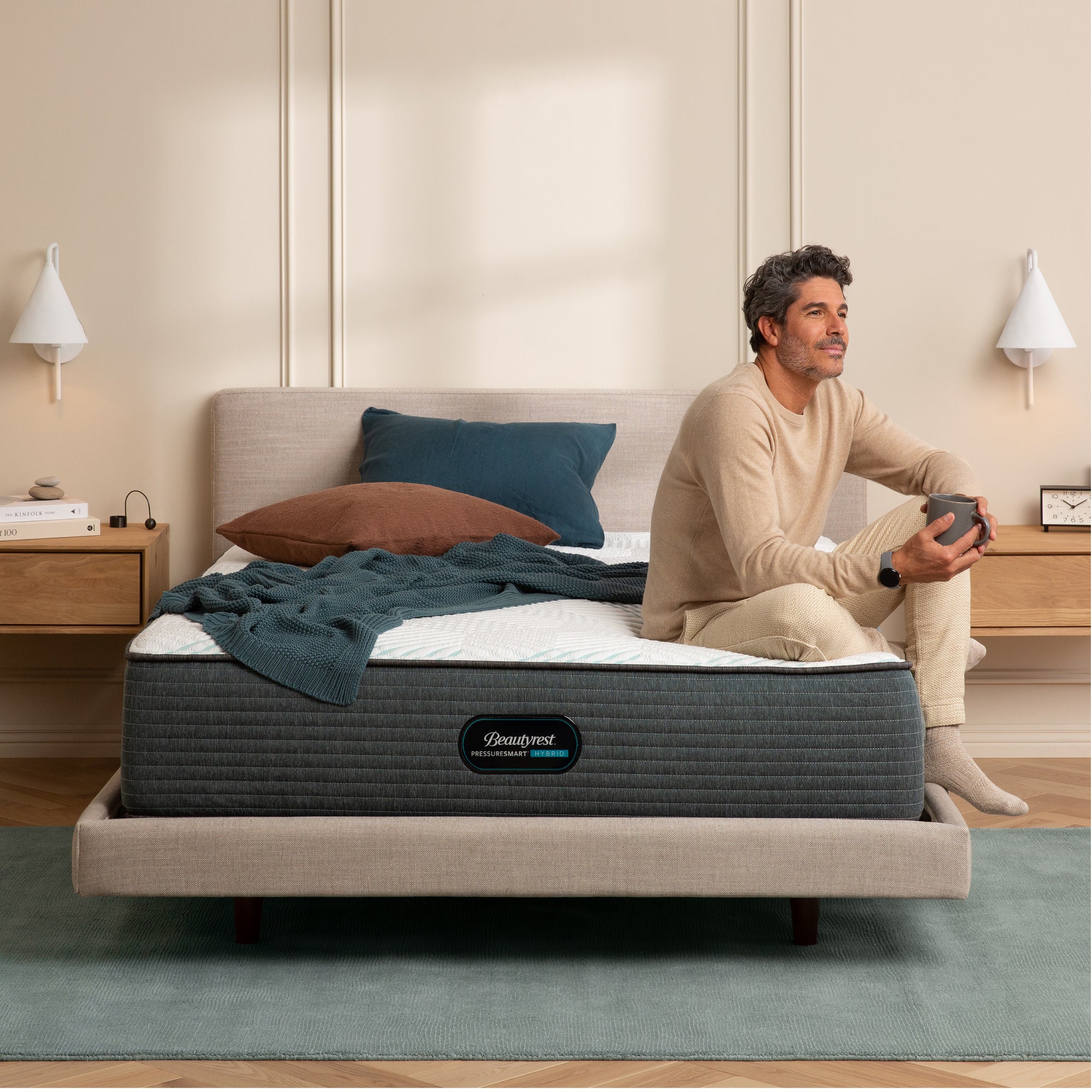 Man drinking coffee while sitting on the Beautyrest PressureSmart mattress||feel: firm||series: hybrid