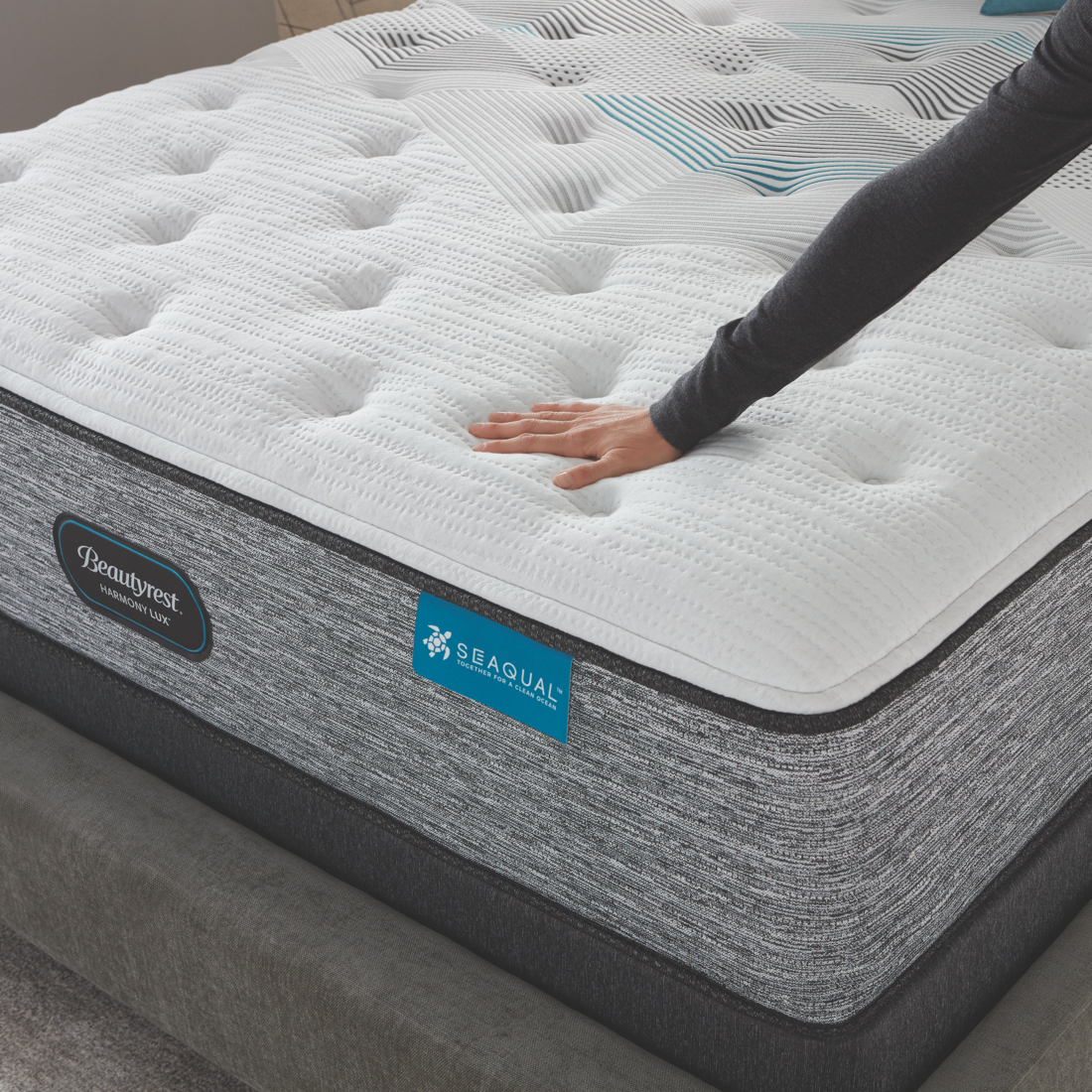 Hand touching the top of a Beautyrest Harmony Lux mattress on top of a Beautyrest flat foundation