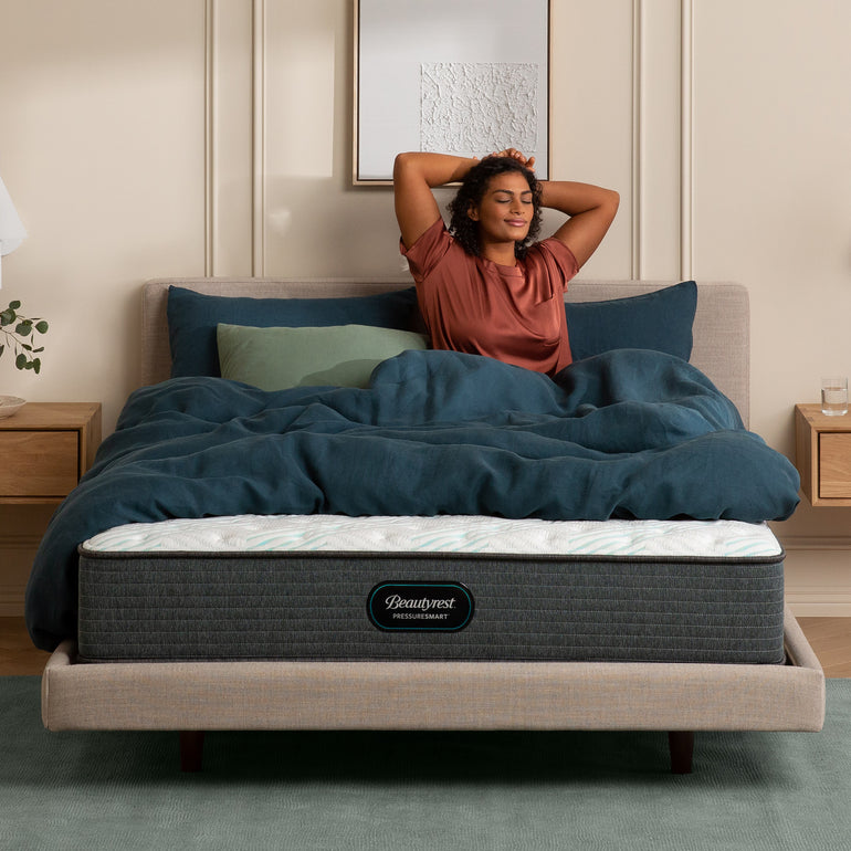 Woman stretching in her bedroom on the Beautyrest PressureSmart mattress || feel: firm || series: standard