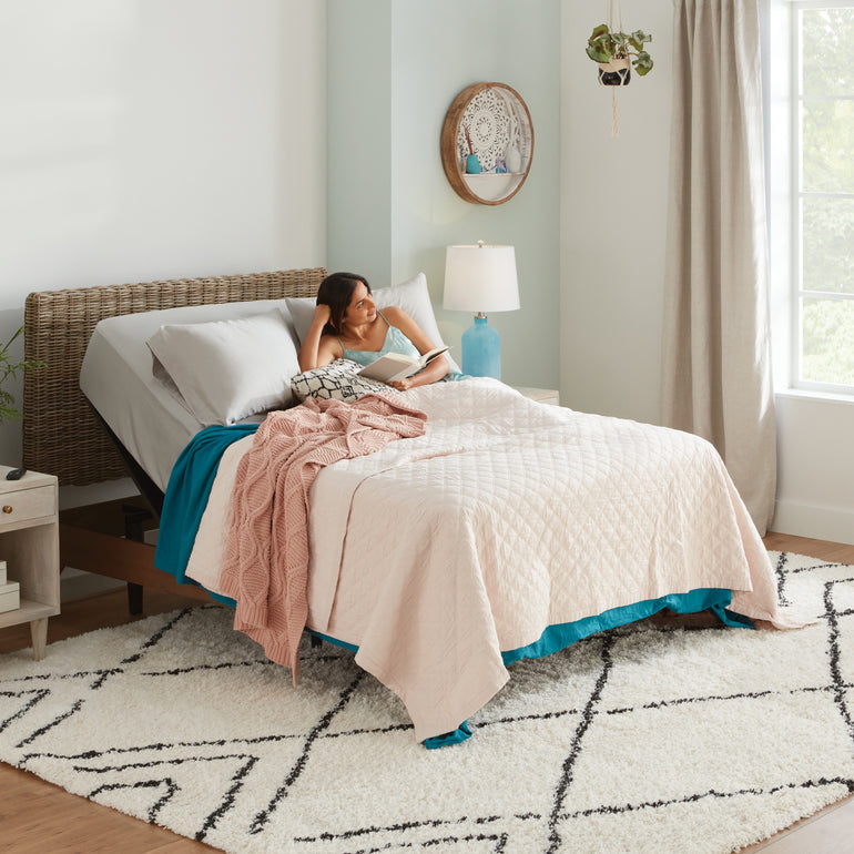 A woman reading in a bedroom, on a mattress with the Beautyrest Motion Air adjustable base