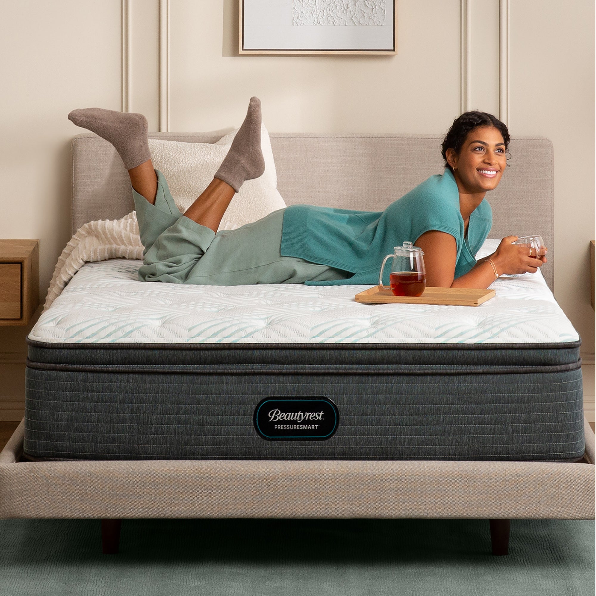 Woman drinking tea while laying on the Beautyrest PressureSmart mattress||feel: plush pillow top||series: standard