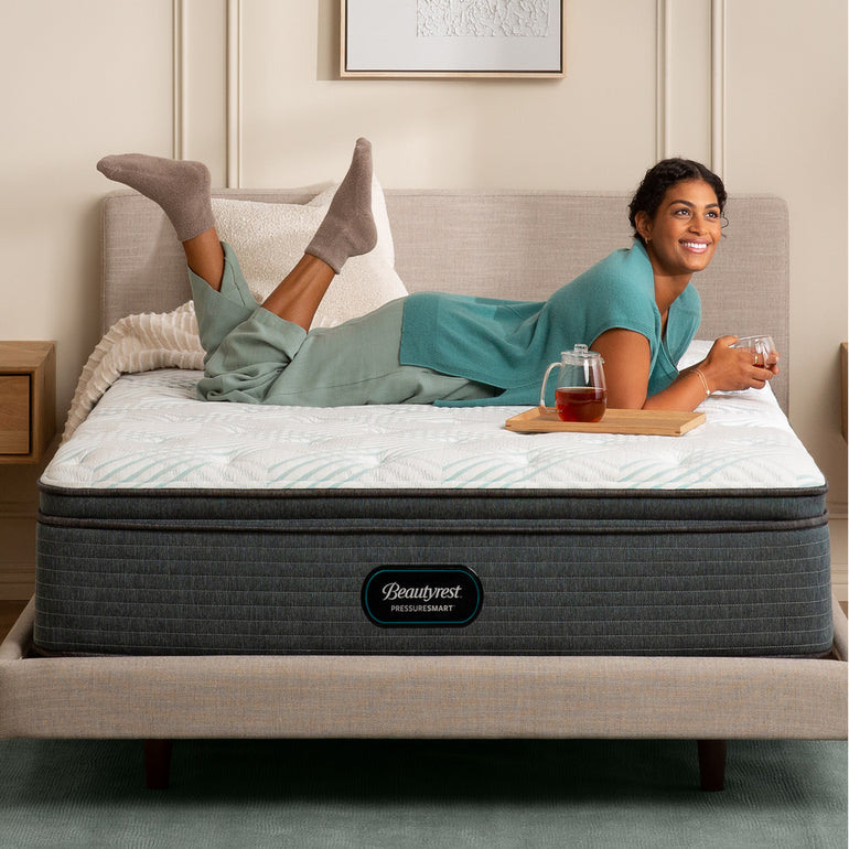 Woman drinking tea while laying on the Beautyrest PressureSmart mattress||feel: plush pillow top||series: standard