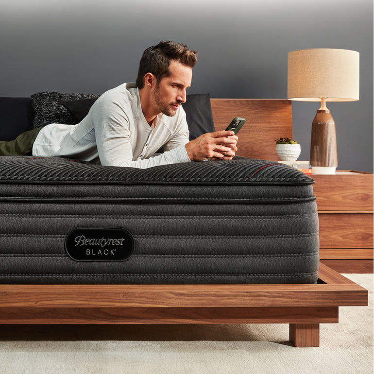 Man laying across the Beautyrest Black mattress looking at his phone||series: deluxe c-class||feel: medium pillow top