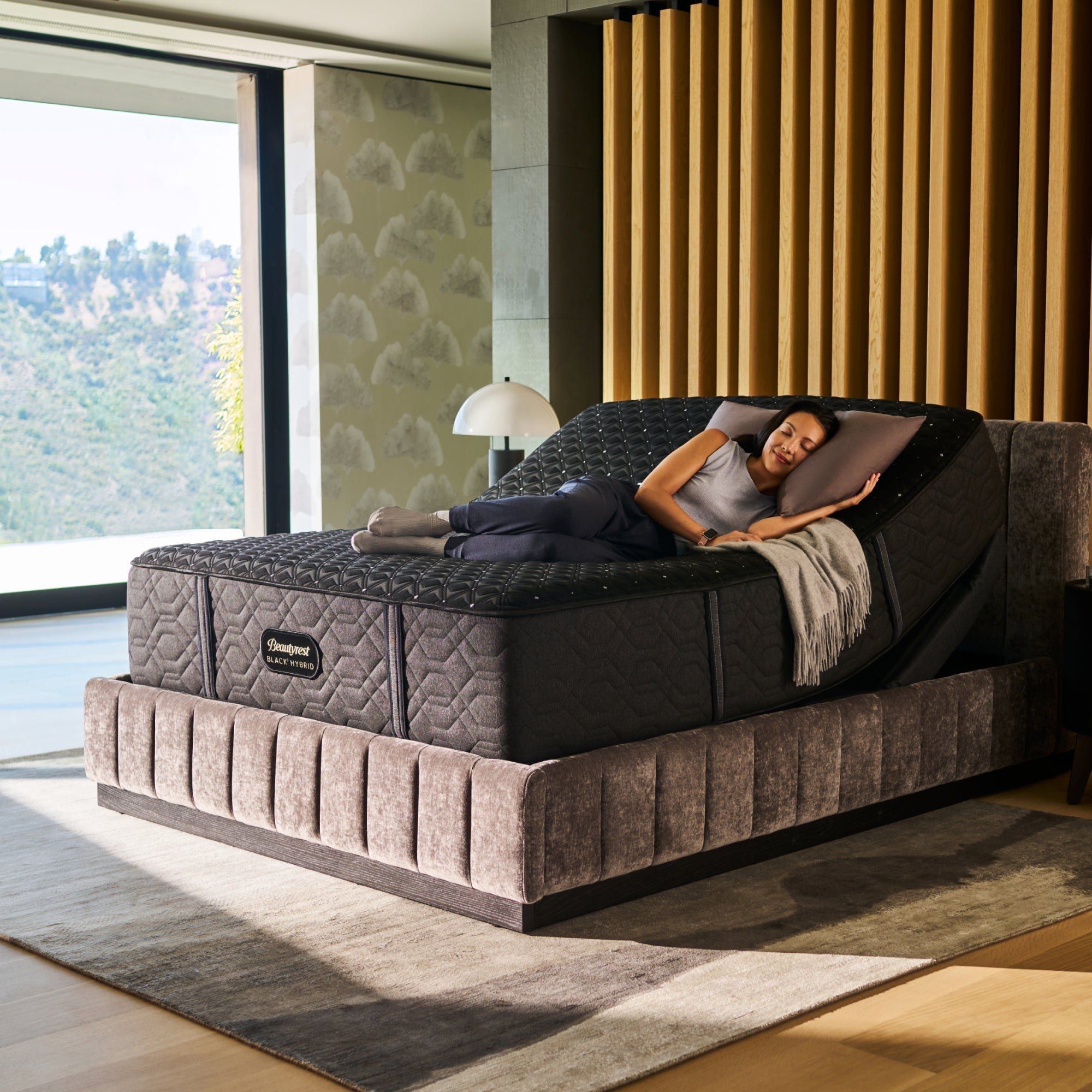 Close-up of a dark upholstered bed with a quilted mattress, modern bedroom setting in the background.